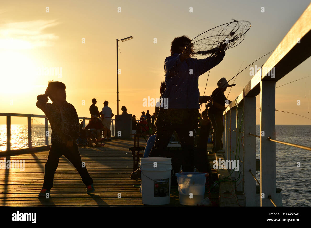 Siluetas de gente pescando en la escollera de semáforo en el sur de Australia al atardecer Foto de stock