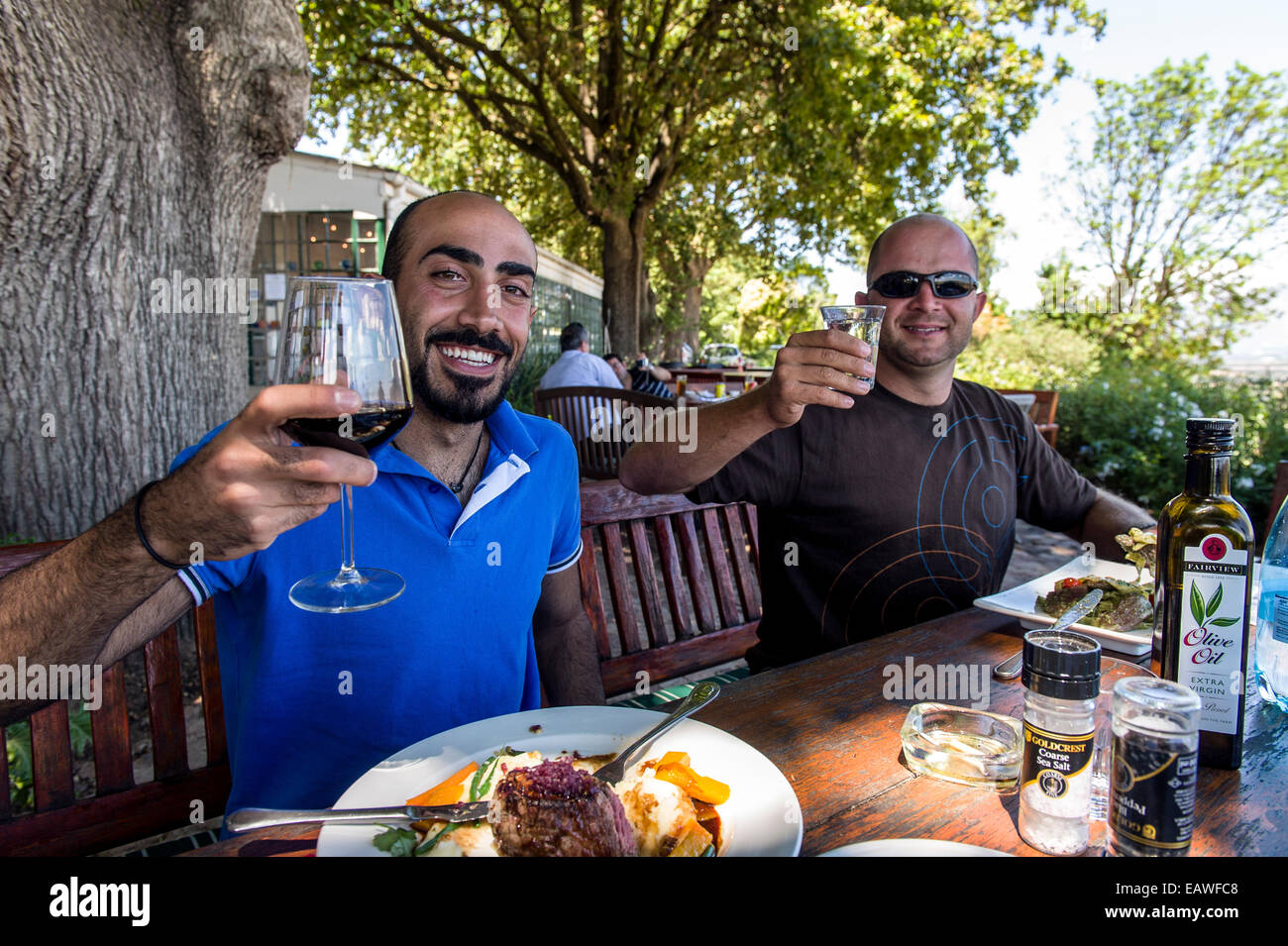 Los turistas disfrutan de la comida gourmet y excelentes vinos en un viñedo de restaurante. Foto de stock