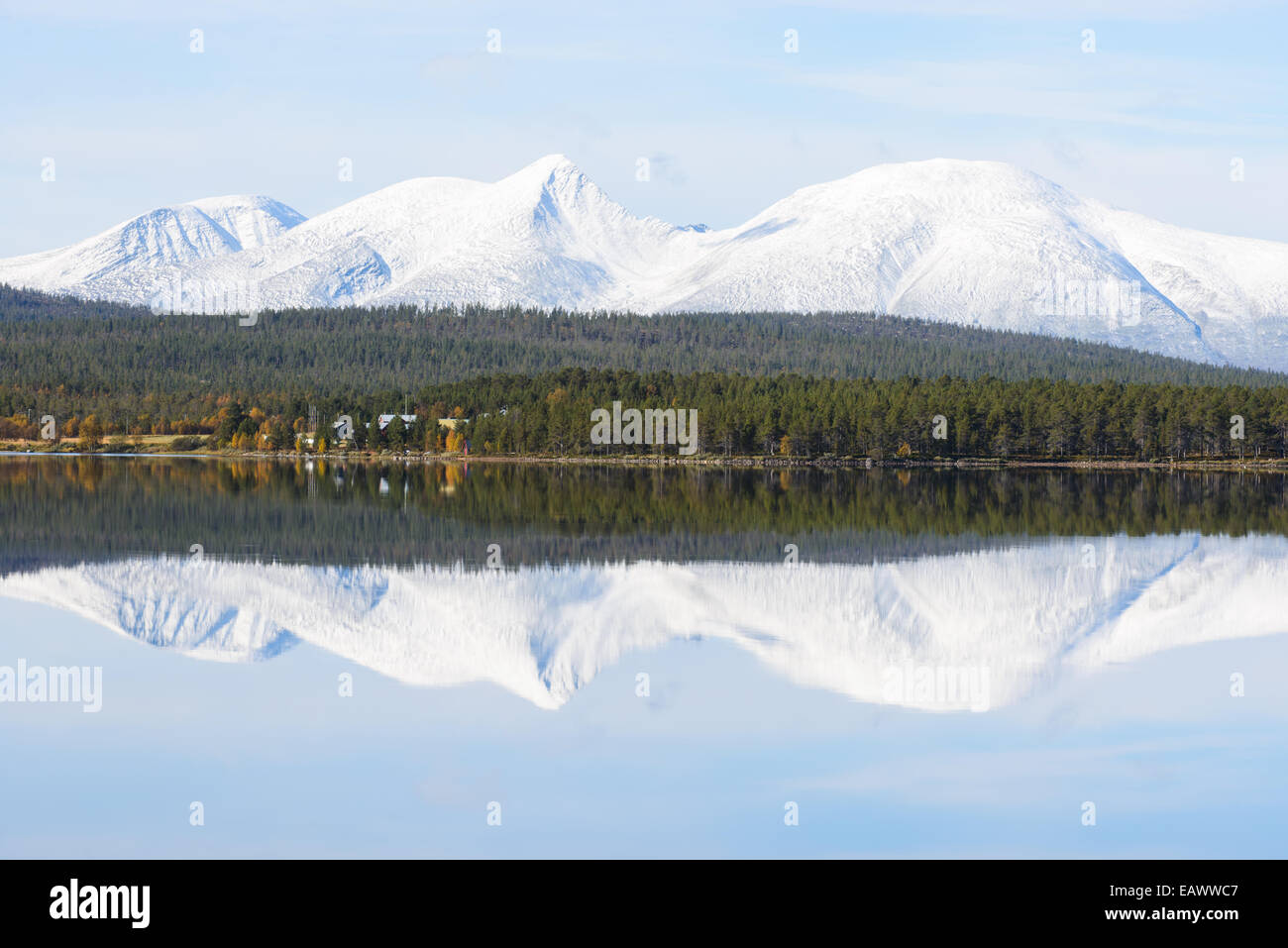 Montaña nevada y un bosque verde reflejada en un lago Foto de stock