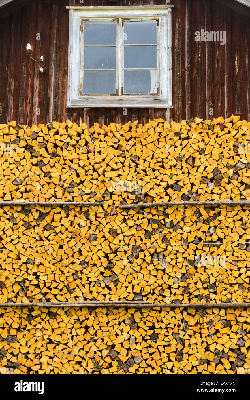 Montón de amarillo troncos apilados contra una pared de cabina Foto de stock