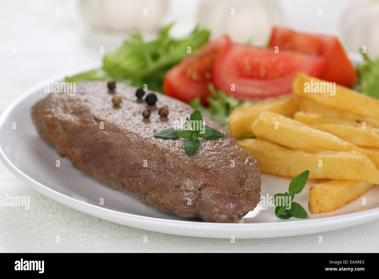 Filete de ternera con papas fritas en harina de carne, verduras, tomate y lechuga en la placa Foto de stock