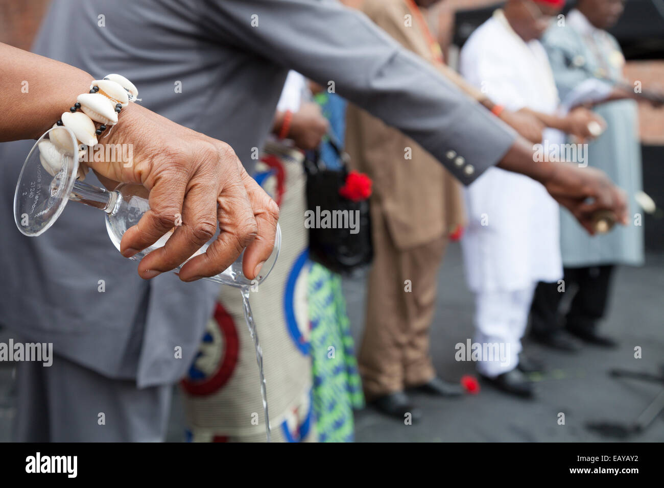 El alcohol se vierte en un vaso durante una ceremonia de libación de África. Foto de stock