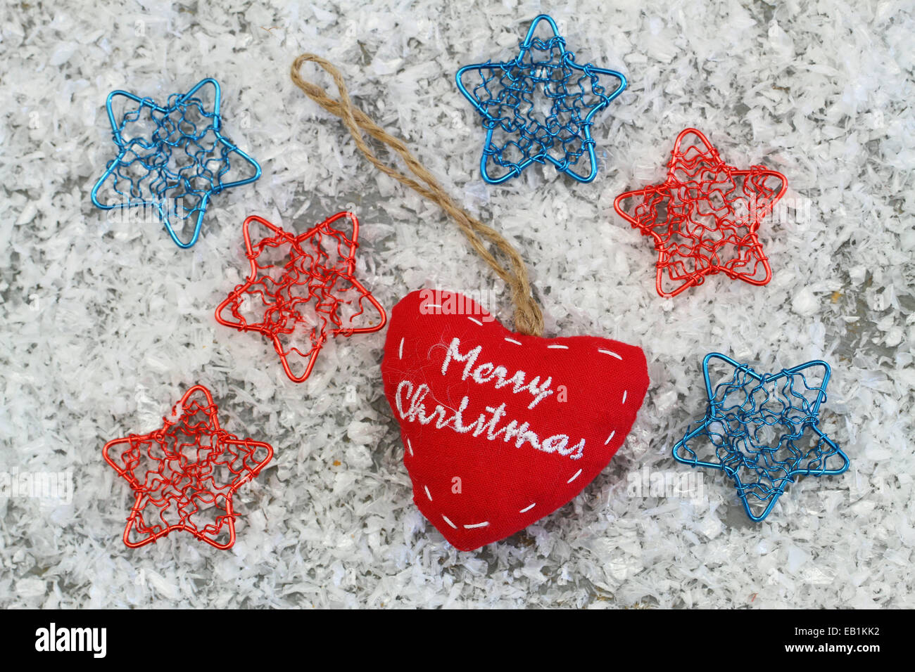 Feliz Navidad corazón con coloridas estrellas en superficie de nieve Foto de stock