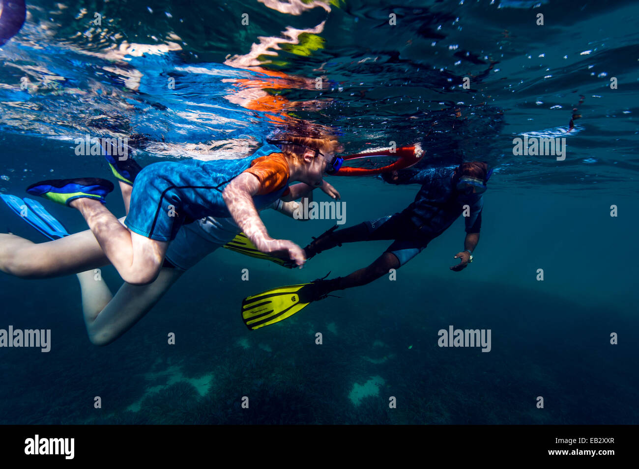Un instructor de buceo ayuda a un niño pequeño para hacer snorkel en un arrecife de coral tropical flotante utilizando un anillo de rescate. Foto de stock
