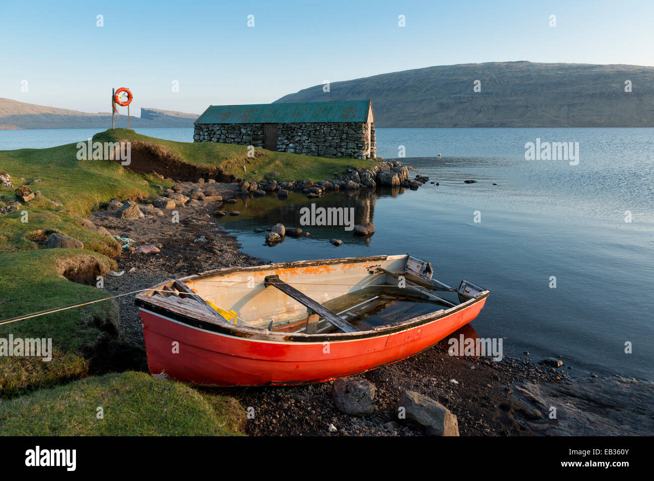 El barco rojo delante de una casa del barco en el lago Sørvágsvatn o Leitisvatn, Vágar, Islas Feroe, Dinamarca Foto de stock