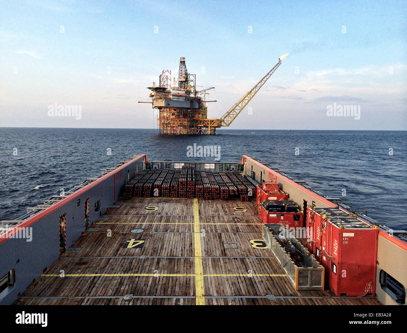 Embarcación náutica que se acerca a una plataforma petrolífera al amanecer Foto de stock