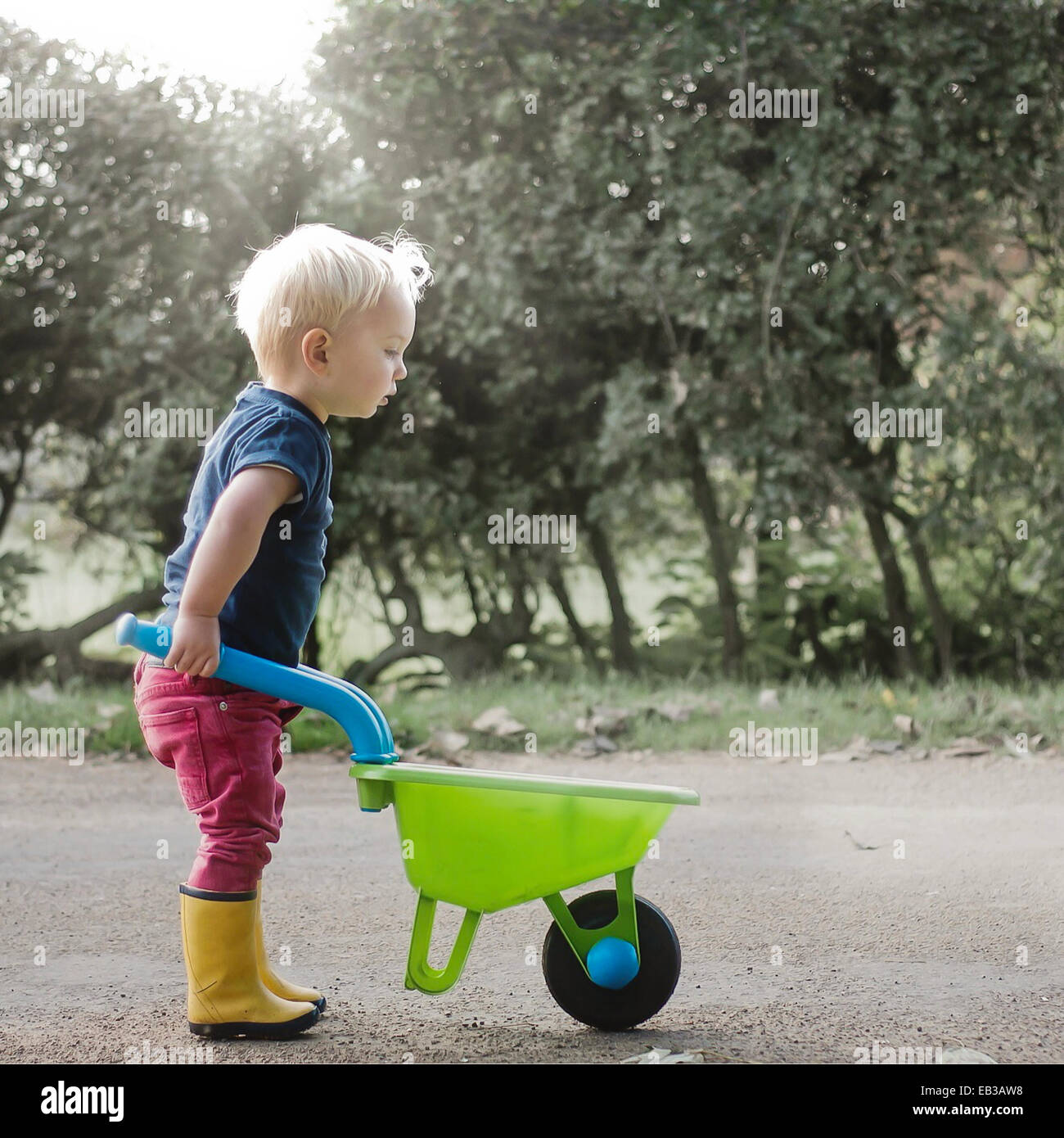 Niño empujando una carretilla de juguete Fotografía de stock - Alamy