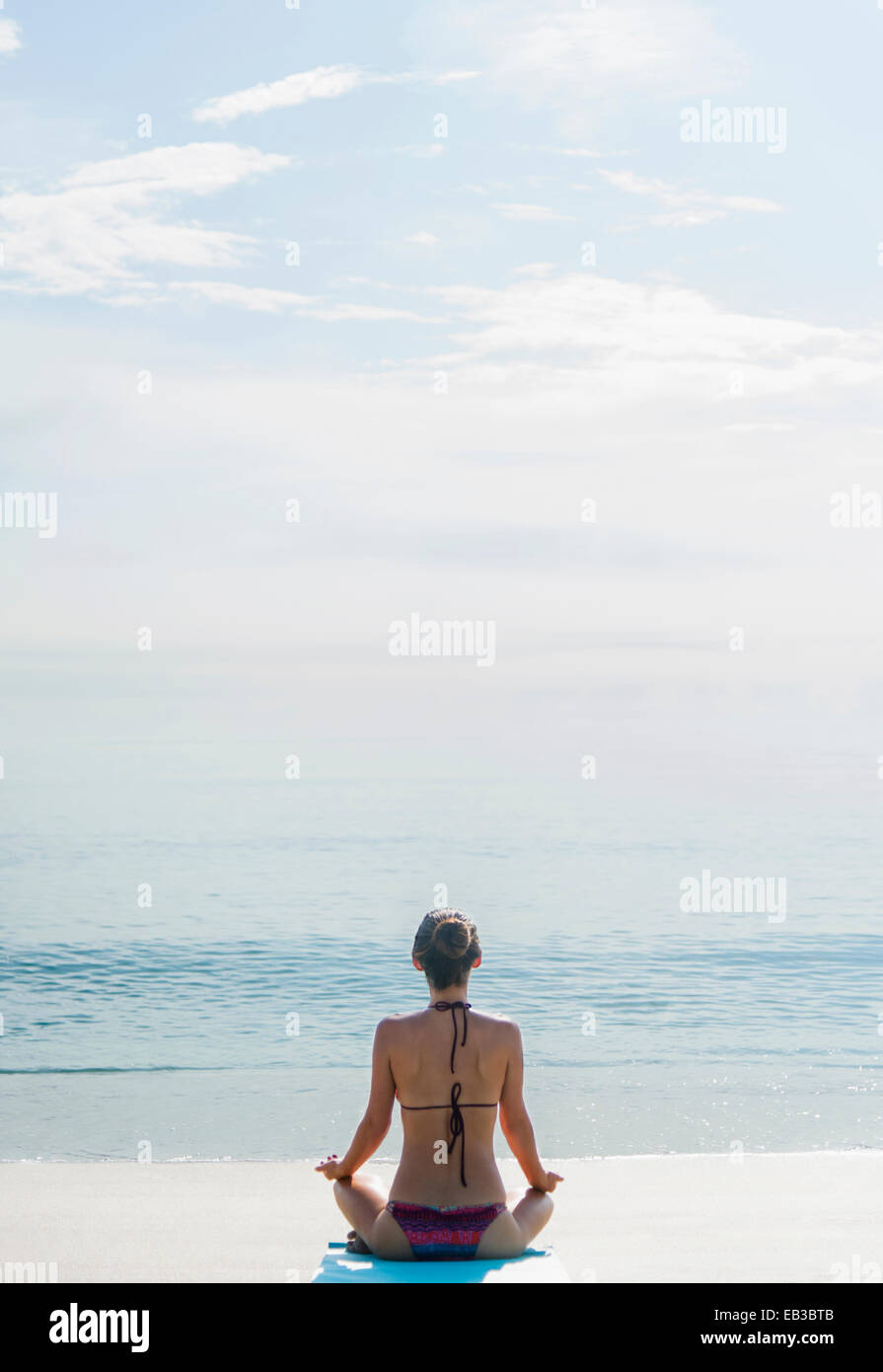 Mujer caucásica meditando en la playa Foto de stock