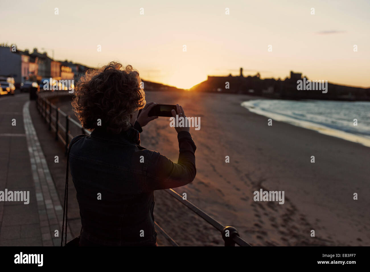 Mujer toma iphone foto de Sunset y el castillo Foto de stock