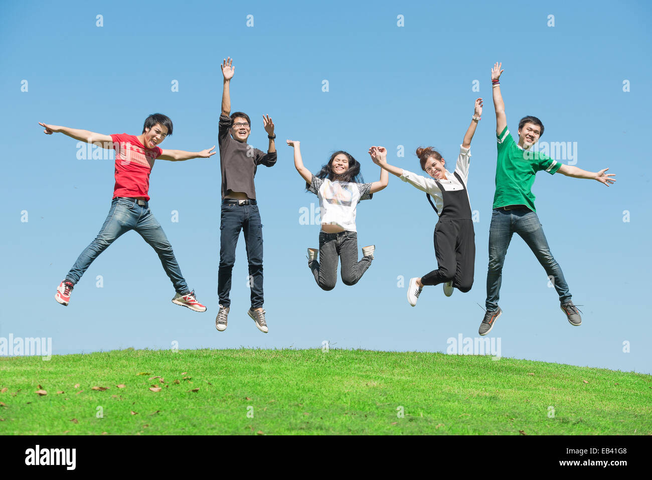 Verano, vacaciones, vacaciones, gente feliz concepto - grupo de amigos saltando sobre el parque Foto de stock