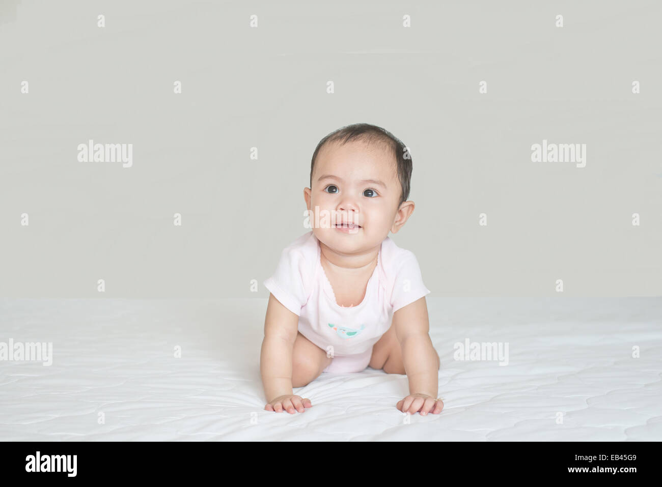 Cute Asia niña bebe gateando en dormitorio Foto de stock