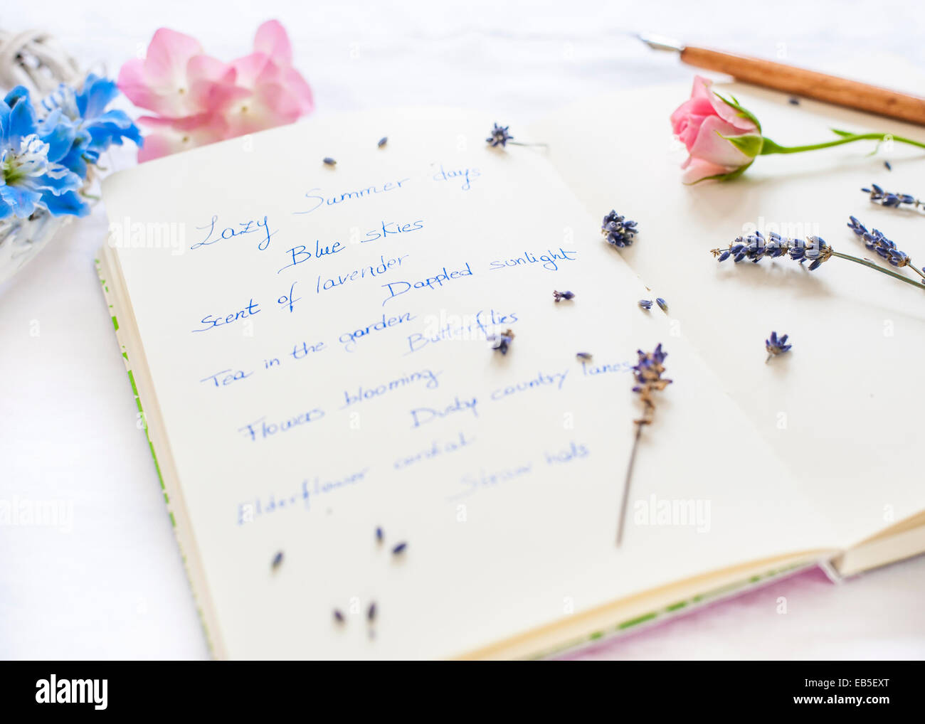 Bloc de notas con notas sobre el verano, pluma, lavanda, Delphinium, rosa rosa y hortensias - enfoque selectivo con desenfoque Foto de stock