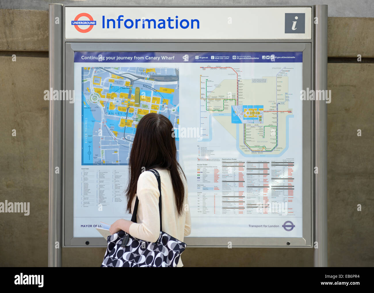 Mujer mirando un mapa de la ciudad con información sobre viajes, Canary Wharf, London, UK. Foto de stock