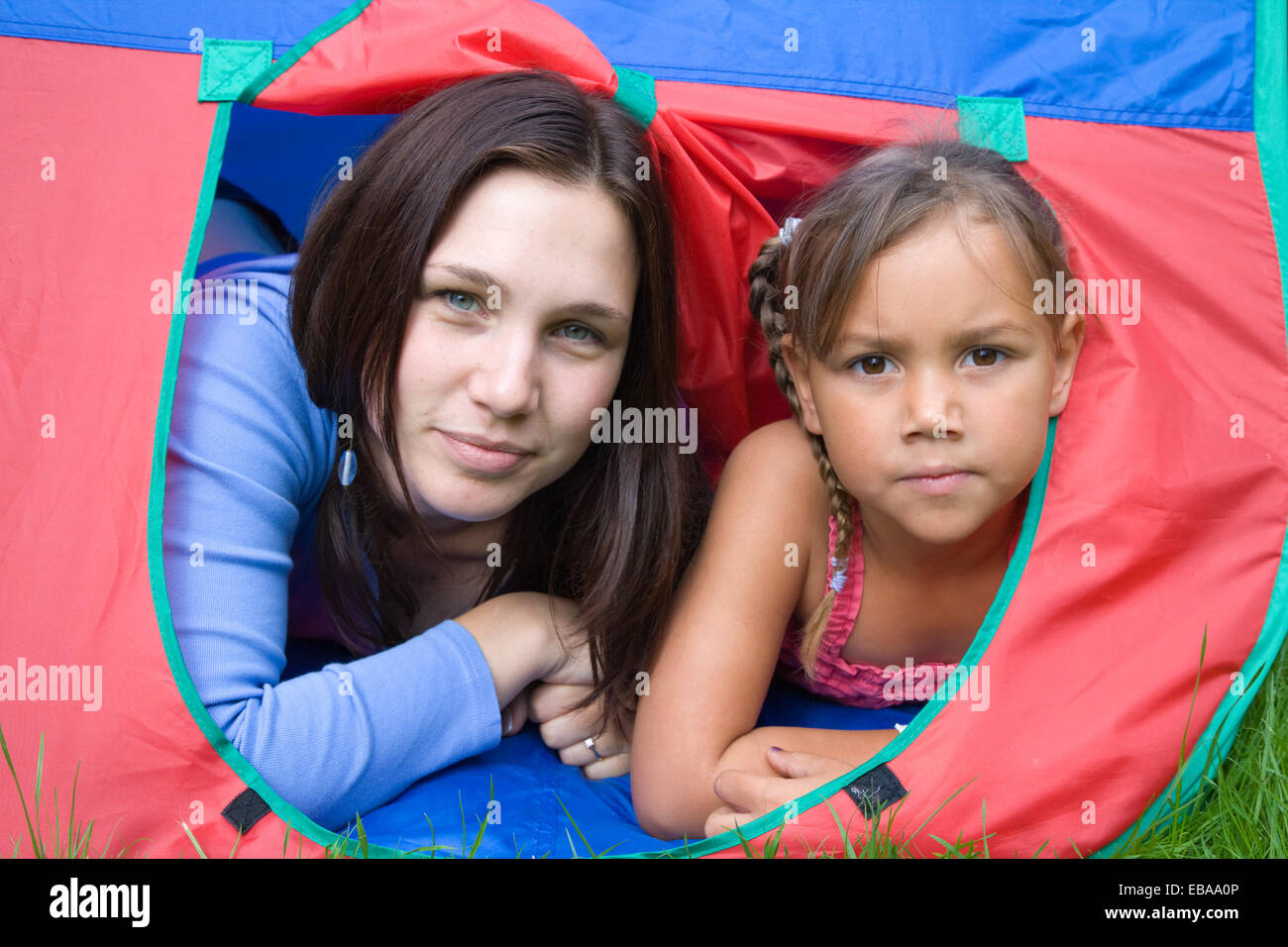 Madre e hija jugando en un túnel en el jardín, Foto de stock