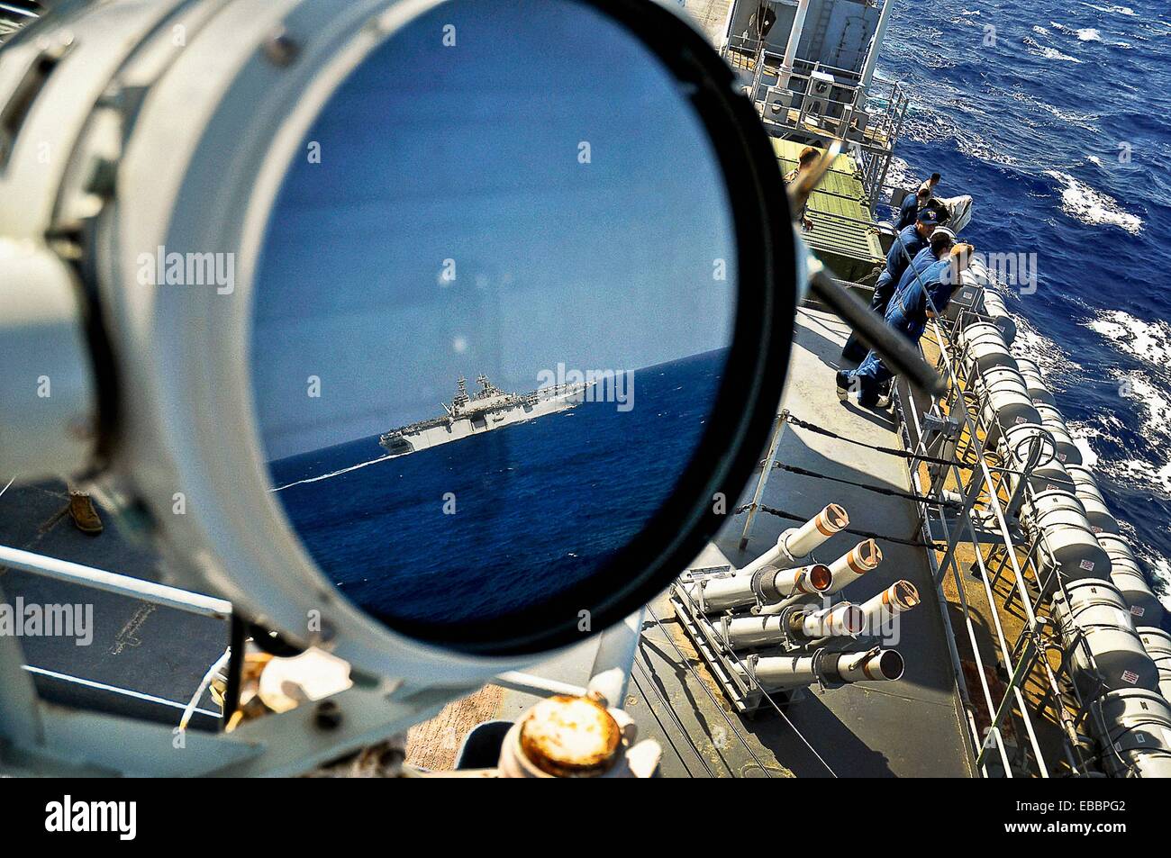 Reflejado en una lámpara de señal, el buque de asalto anfibio USS Kearsarge pasa el muelle de transporte anfibio USS Ponce Ponce Foto de stock