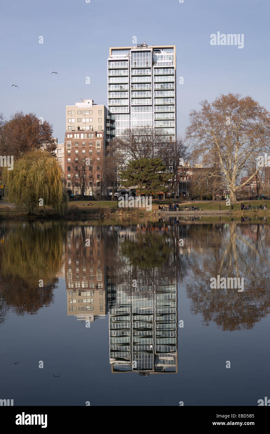 Los edificios reflejan en la superficie del Harlem Meer (lago) en Central Park, New York. Foto de stock