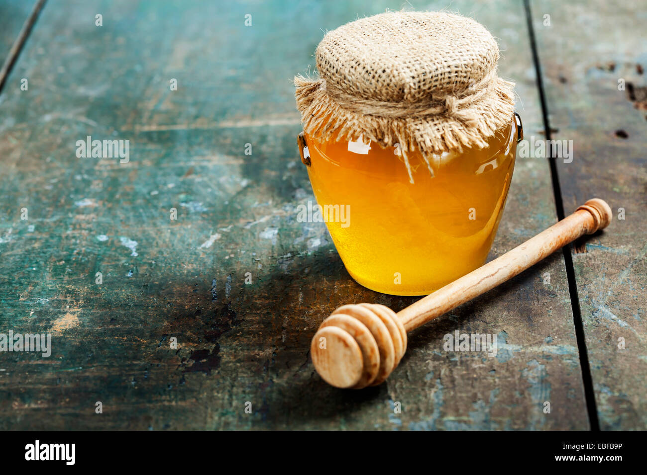 Tarro de miel y penetrador sobre fondo de madera Foto de stock