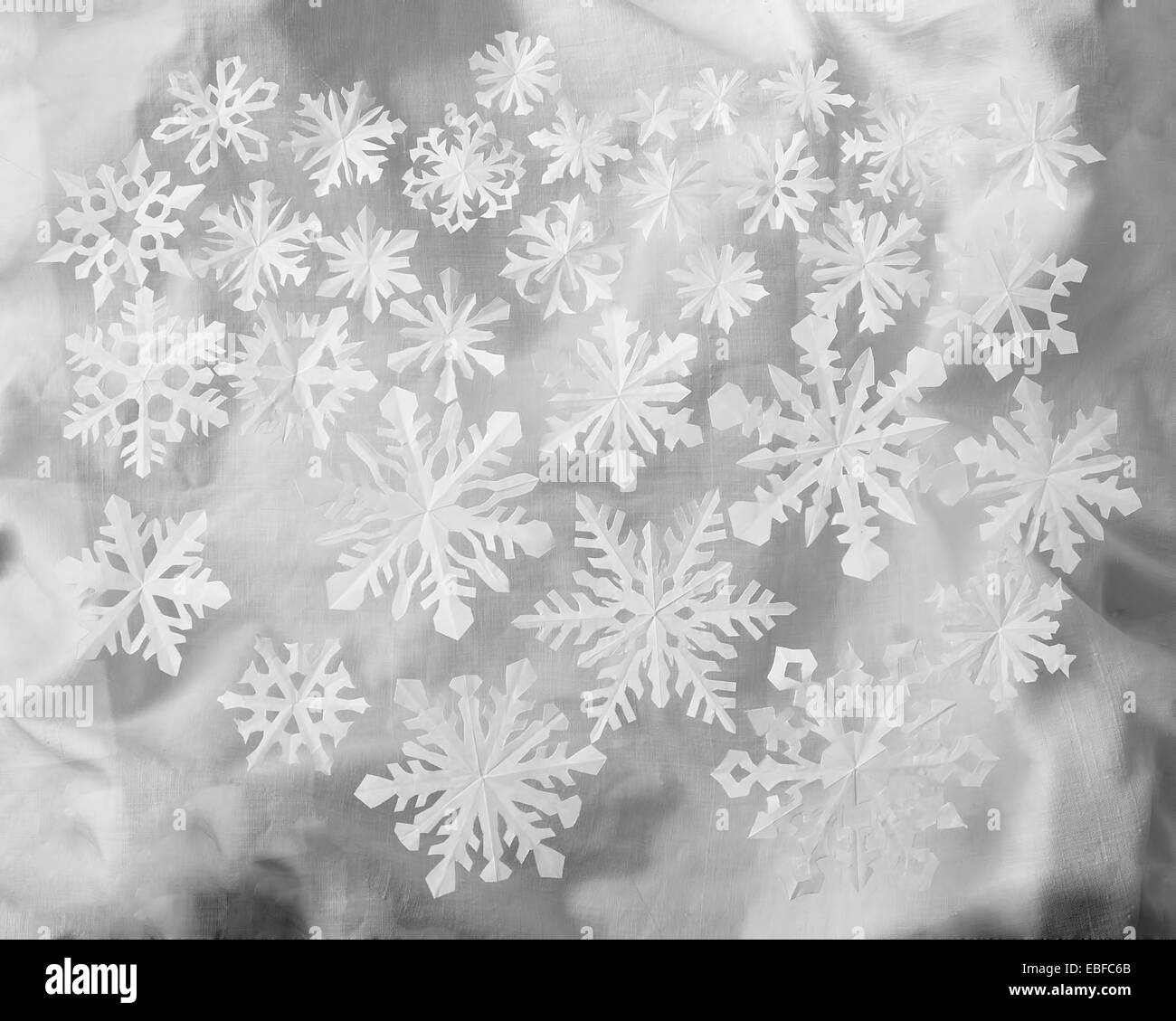 Los copos de nieve de papel sobre tela brillantes antecedentes Foto de stock