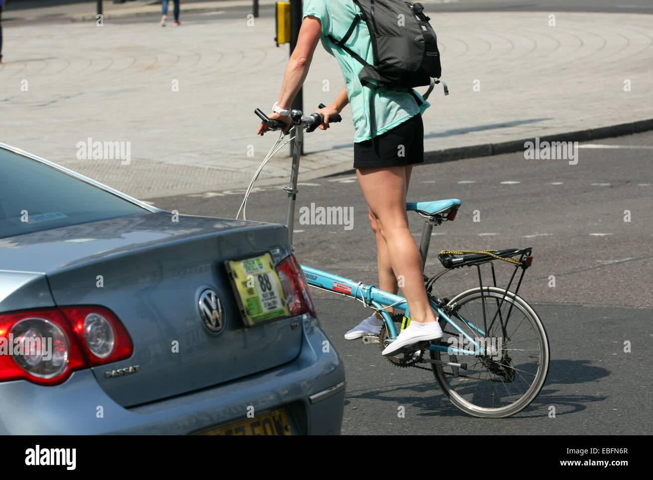 Un ciclista en una bicicleta plegable bicicleta junto a un coche en Londres Foto de stock