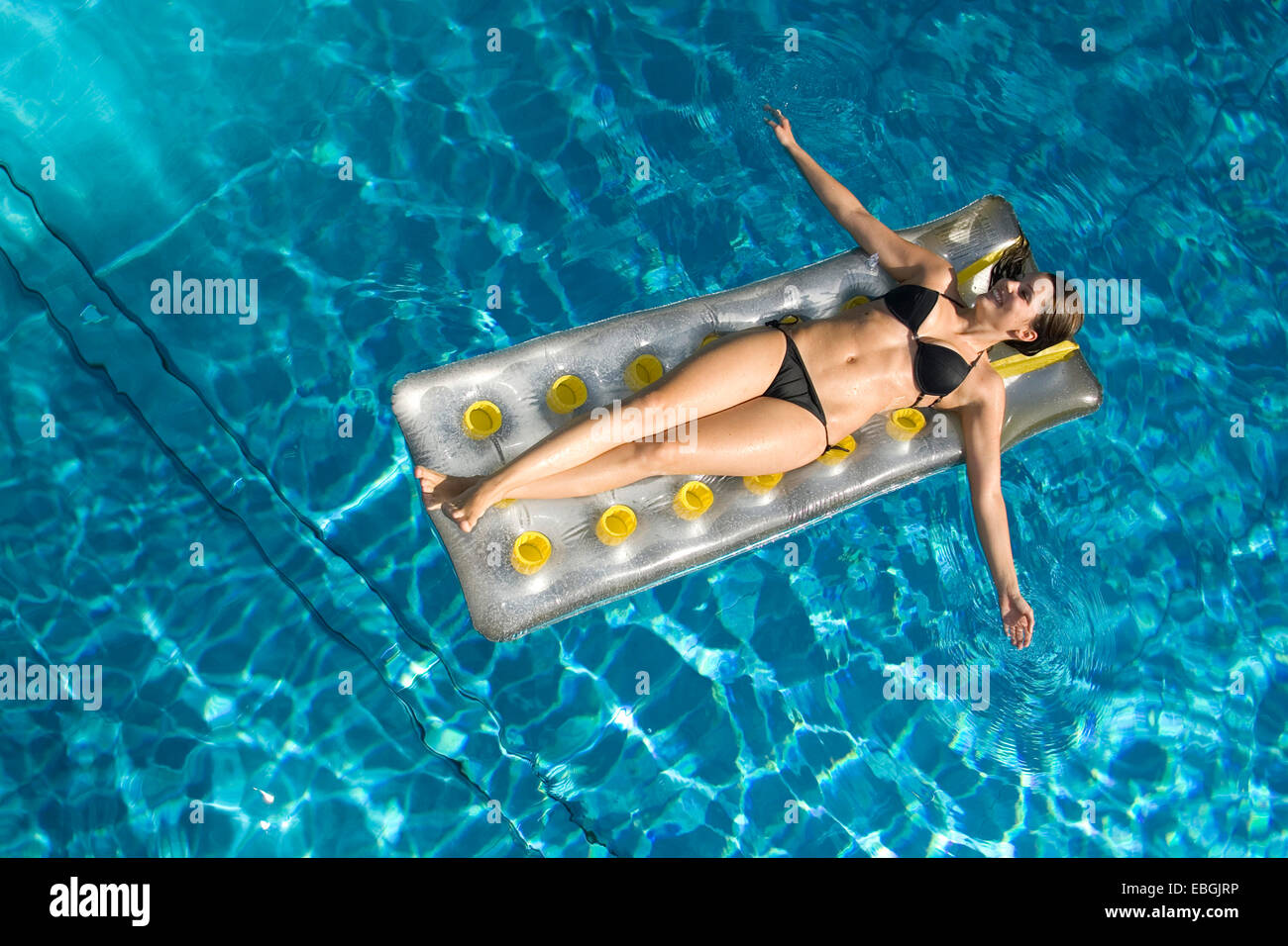 Mujer joven sobre colchón de aire en una piscina, Austria Foto de stock