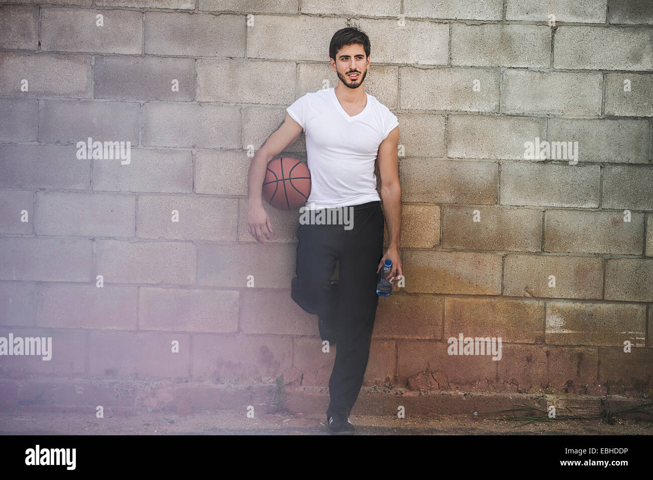Joven jugador de baloncesto masculino contra la pared inclinada Foto de stock
