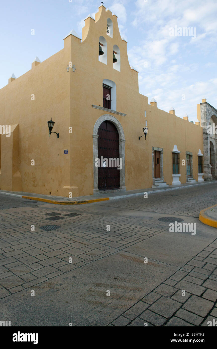 Vista de esquina de la iglesia de la Iglesia de San Francisco del siglo XVI con estuco de color ocre, puerta frontal con arco rojo, tres campanas en Campeche, MX. Foto de stock