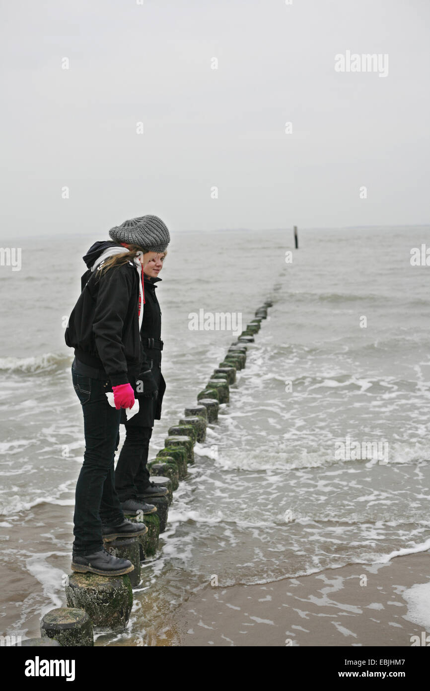 Dos mujeres jóvenes en equilibrio espigón de madera, Holanda, Zelanda, Breskens, Sluis Foto de stock