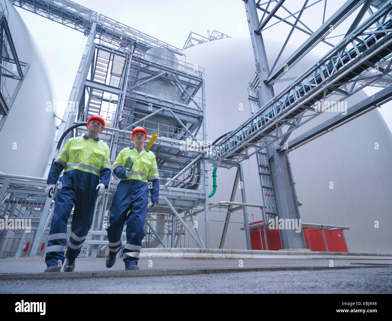 Los trabajadores caminando a través de instalaciones de biomasa, bajo ángulo de visión Foto de stock