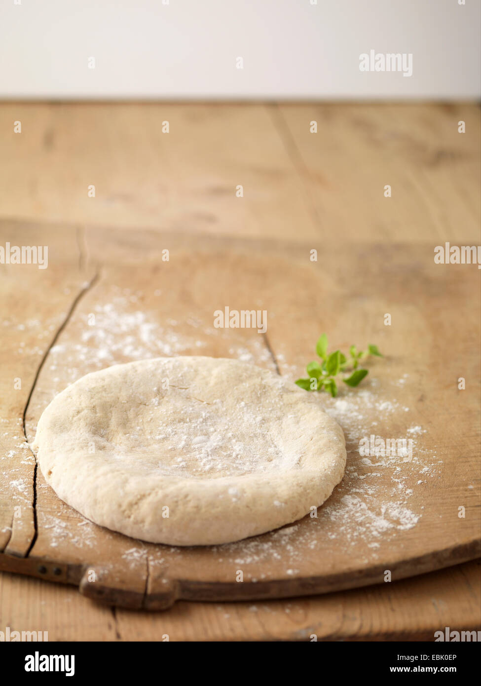 Círculo de masa para pizza preparada sobre una tabla de cortar espolvoreado con harina Foto de stock