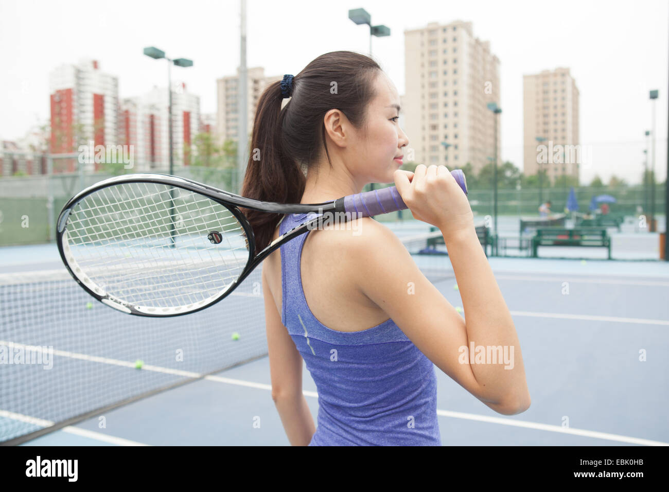 Joven Jugador de tenis femenino con la raqueta de tenis sobre el hombro de cancha de tenis Foto de stock