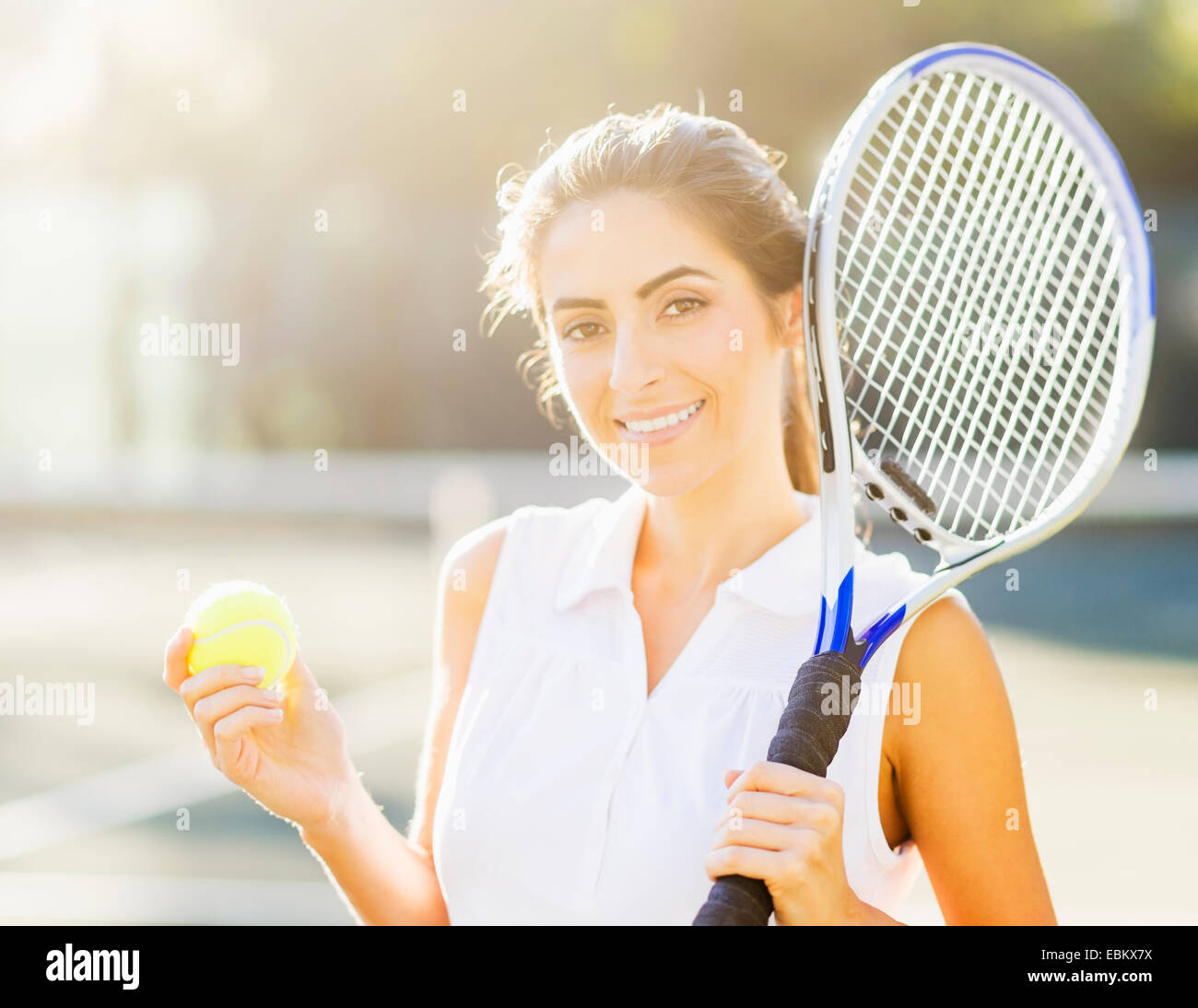 Retrato de mujer joven sosteniendo pelota de tenis y raqueta de tenis Foto de stock