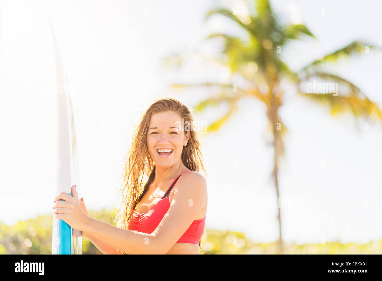 Ee.Uu., Florida, Júpiter, Retrato de mujer joven celebración de surf en la playa Foto de stock