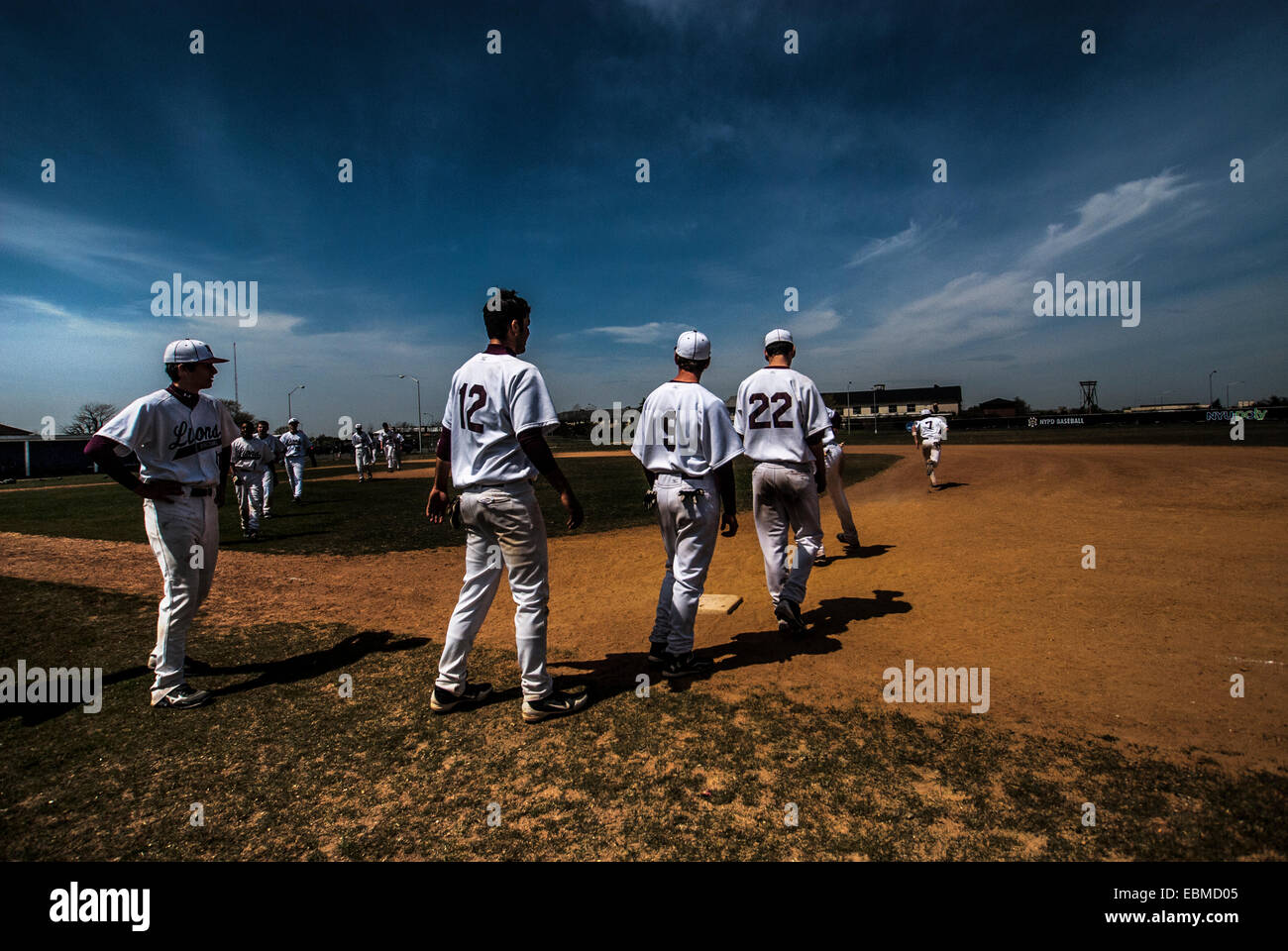 Equipo de béisbol de los muchachos caminando hacia el campo de béisbol con una sobrecarga de Big Sky Foto de stock