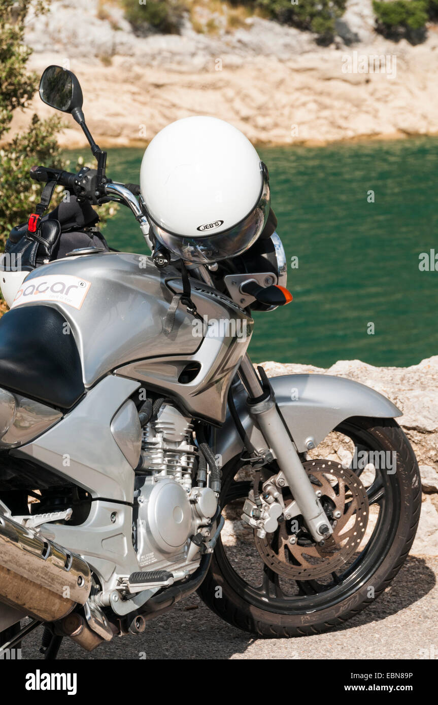 Casco colgando en el manillar de una moto estacionada junto a un lago en  Mallorca Fotografía de stock - Alamy
