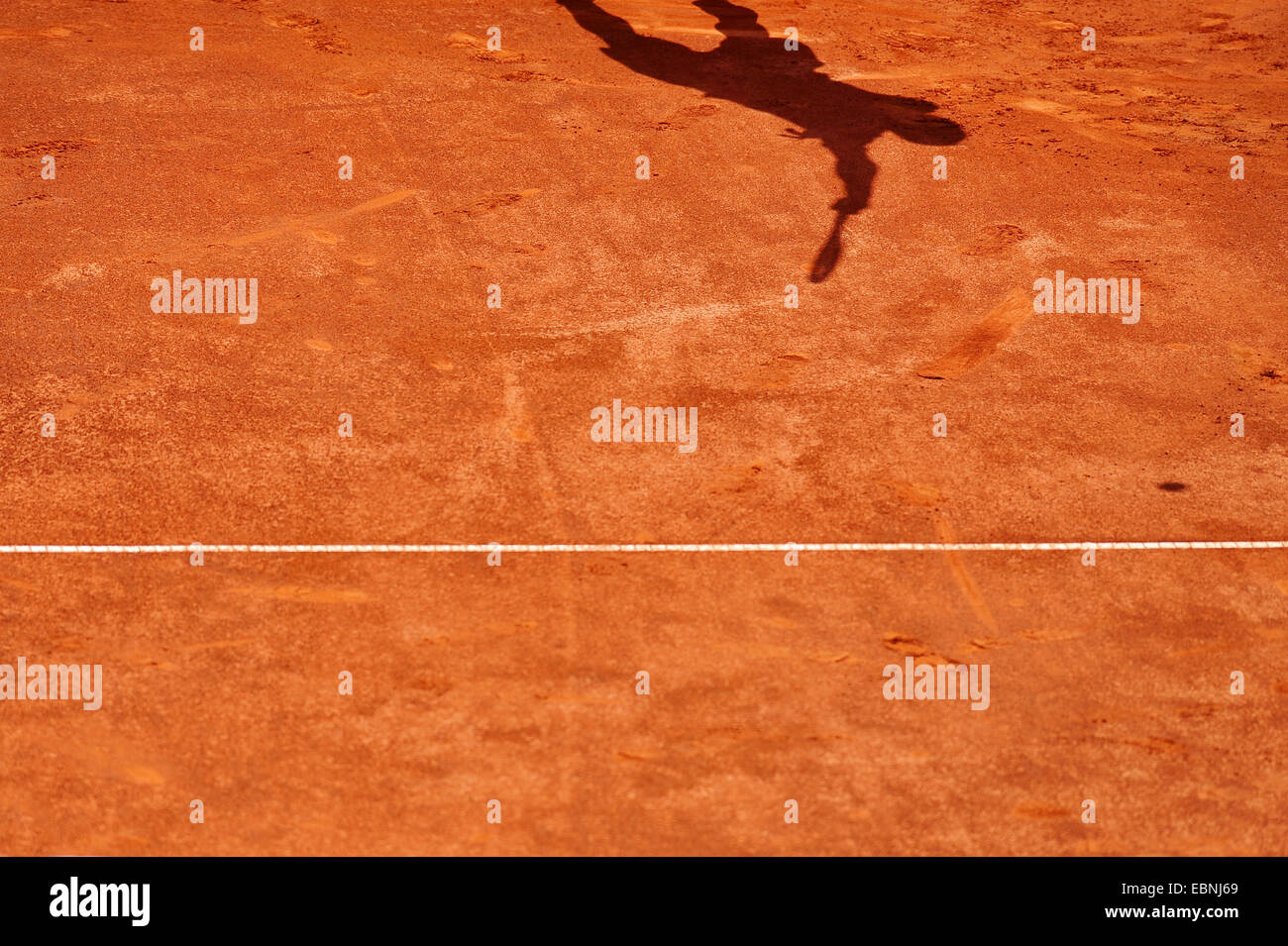 Sombra de un jugador de tenis que sirve en un tribunal de arcilla Foto de stock
