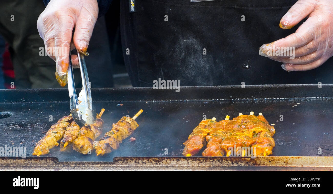 Brochetas de carne cocinar en una parrilla en un mercado. Comida en la calle. Foto de stock