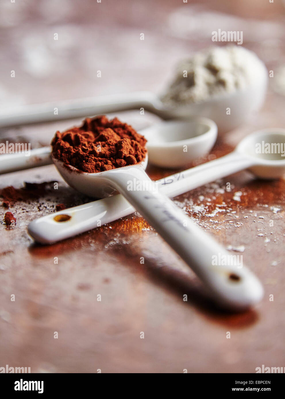 Las cucharas medidoras blanco con cacao y harina sobre una tabla de madera  Fotografía de stock - Alamy