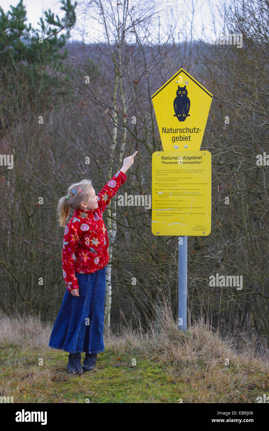 Chica apuntando a una zona de conservación firmar Pantener Moorweiher, Alemania Foto de stock