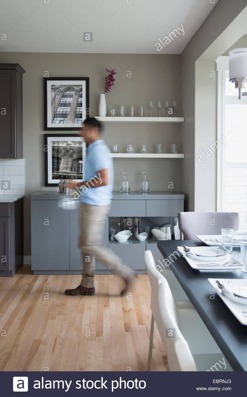 Hombre caminando con copas de vino en la cocina Foto de stock
