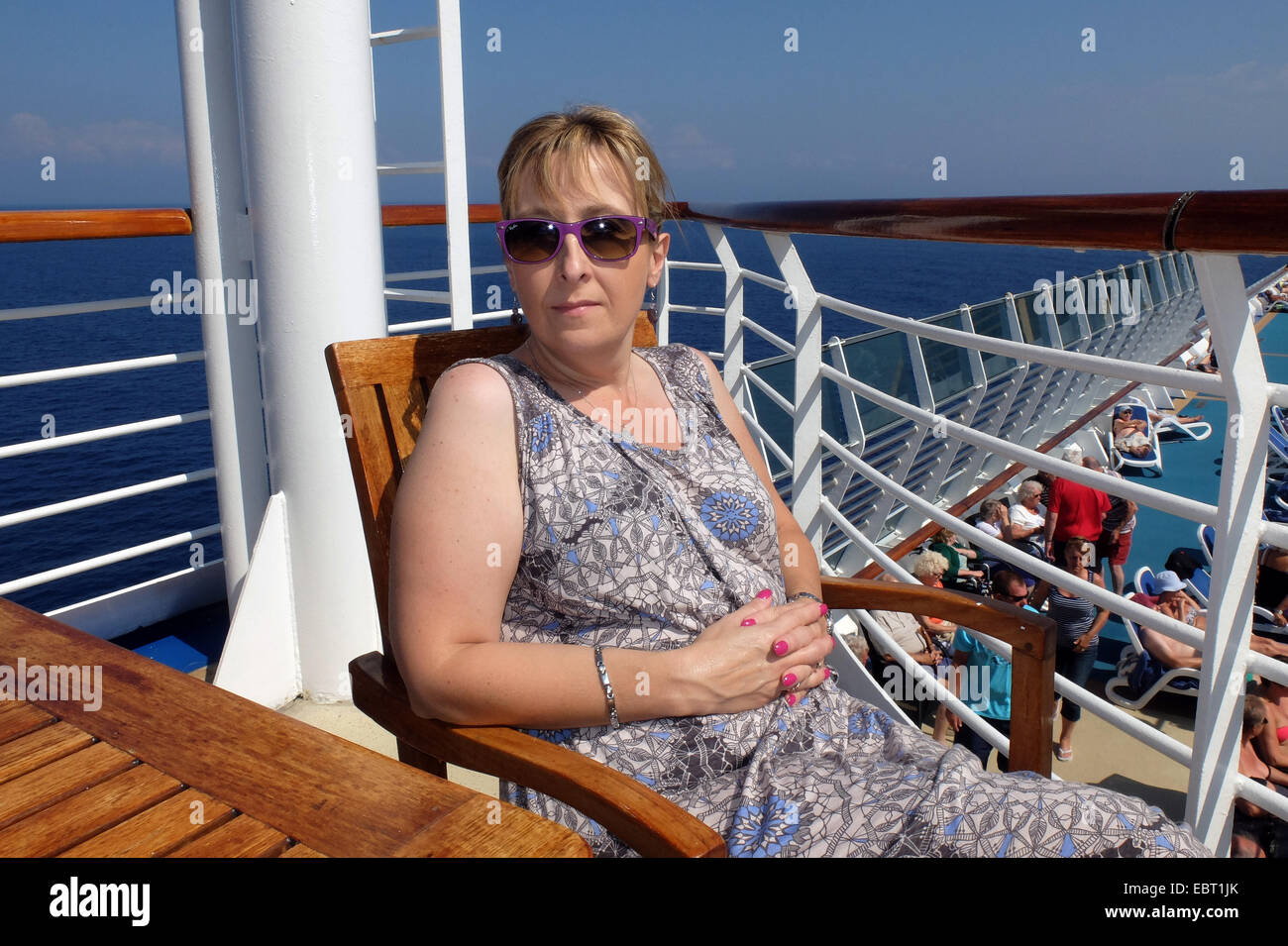 Un pasajero de crucero femenino goza del sol en una cálida tarde de sol en la cubierta Foto de stock