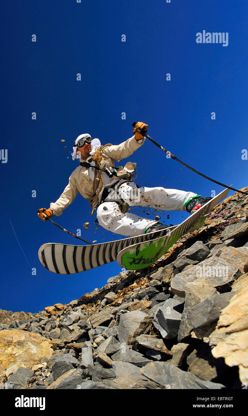 Esquiador freeride disfrazado como antigua aventurero va cuesta abajo en la ladera rocosa Foto de stock