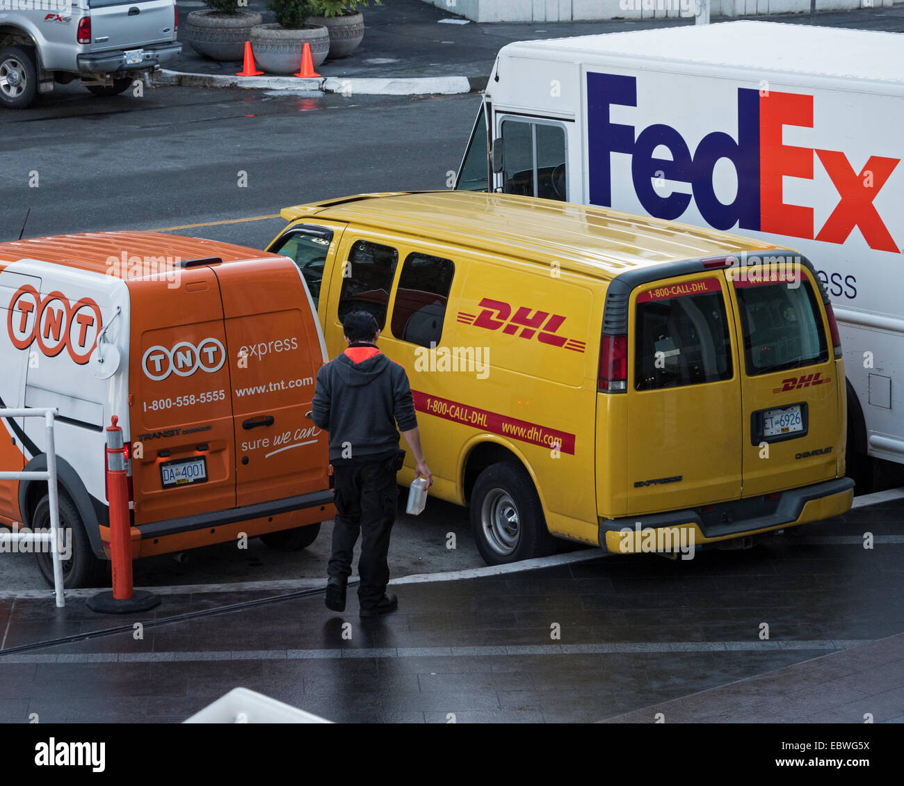 Camionetas de reparto pertenecientes a TNT, DHL y FedEx estacionado en el centro de Vancouver, Canadá Foto de stock