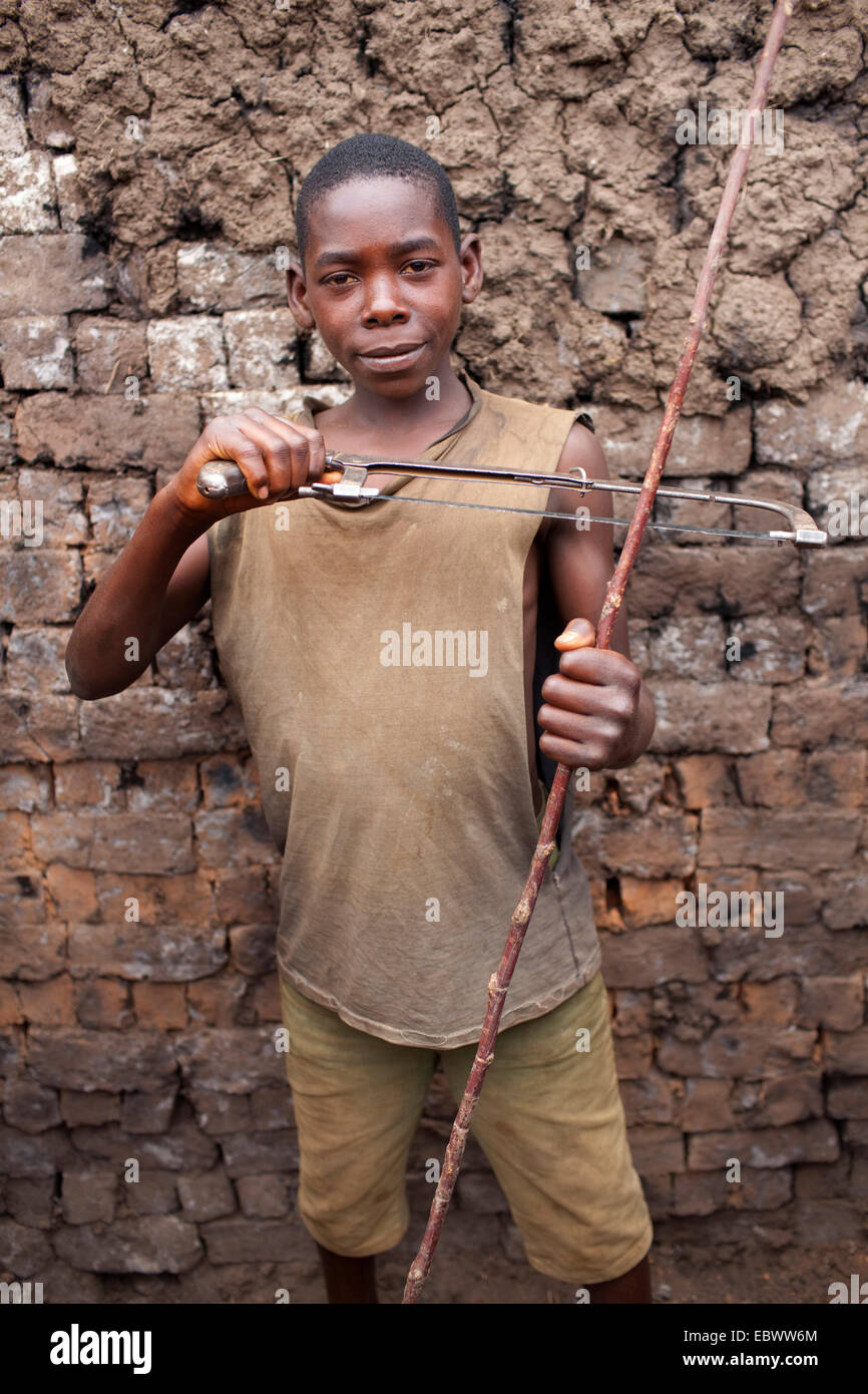 Boy mostrando sierra y rama, Burundi, Karuzi, Buhiga Foto de stock