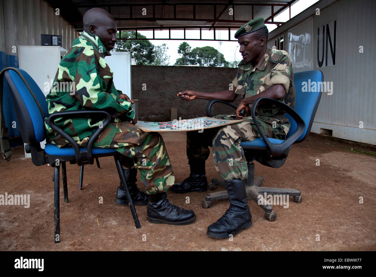 Dos soldados responsables de la seguridad de un campo buero de la ONU están desempeñando los borradores entre recipientes con el logotipo de la organización, Burundi, Makamba, Makamba Foto de stock