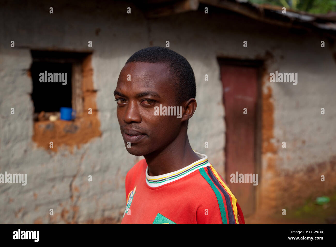 Retrato de un joven delante de una humilde casa de ladrillos de barro, Burundi, Cankuzo, cerca del Parc de la Nacional Ruvubu, Cankuzo Foto de stock