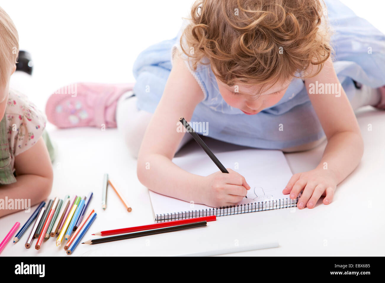 Las niñas tirados en el groud de dibujo con lápices Foto de stock