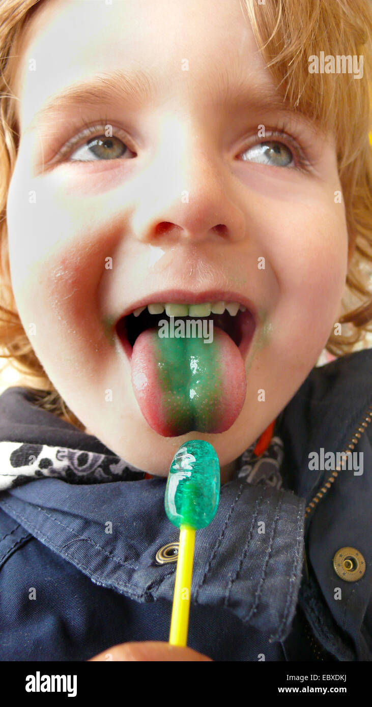 Chico con una lengüeta verde y un verde lolly Foto de stock