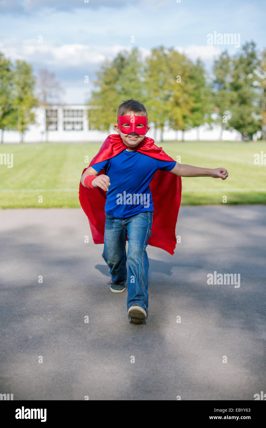 Niño vestido de capa y máscara corriendo hacia delante y Saltar hacia arriba Foto de stock