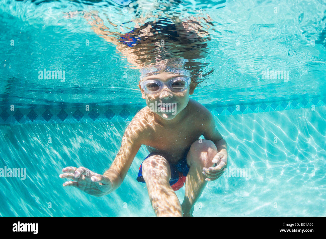 Underwater chico divertido en la piscina con gafas. Divertidas vacaciones de verano. Foto de stock