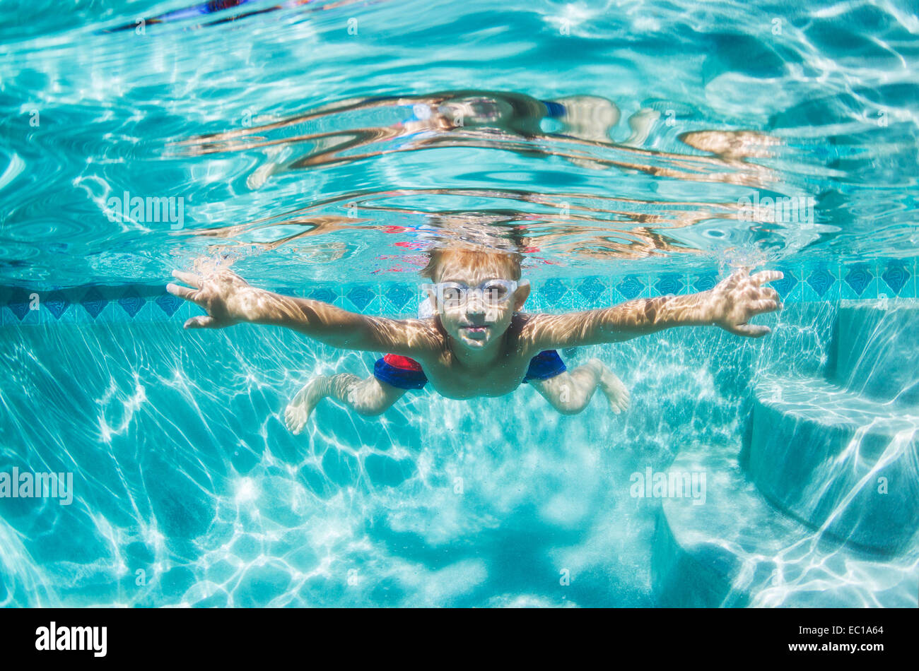 Underwater chico divertido en la piscina con gafas. Divertidas vacaciones de verano. Foto de stock